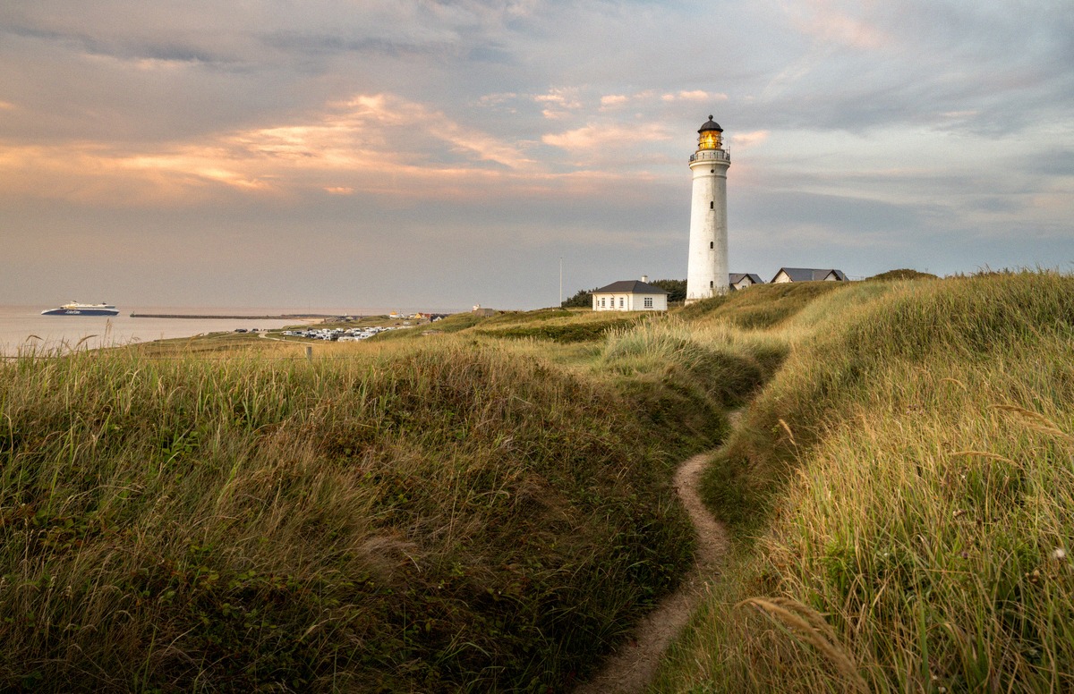 Hirtshals Fyr lighthouse among the dunes, with a ferry on the North Sea behind